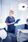 Dentist in mask and blue scrubs using her tablet