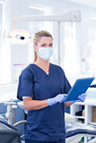 Dentist in mask using her tablet and looking at camera