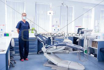 Dentist in blue scrubs standing beside chair