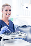 Dentist sitting with tray of tools smiling at camera