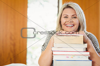 Smiling blonde mature student with stack of books
