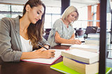 Matures females students writing notes at desk