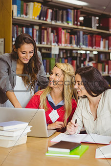 Pretty student showing her classmates something on laptop