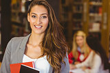 Portrait of a pretty brunette student holding books