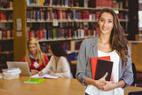 Pretty student holding books with classmates behind her