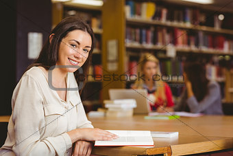 Smiling student sitting at desk reading text book