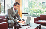Cheerful handsome businessman working at laptop