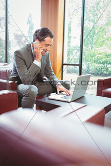 Happy man talking on the phone with his laptop