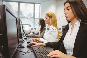Three focused women working in computer room