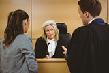 Judge wearing dress and wig listening lawyers