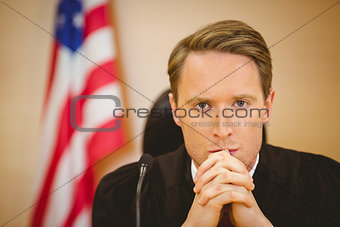 Portrait of a serious judge with american flag behind him