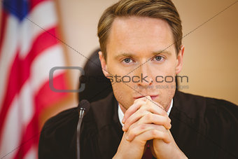 Unsmiling judge with american flag behind him