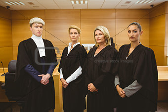 Four serious judges standing while wearing robes