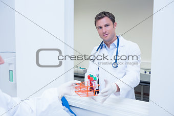 Smiling doctor standing behind blood sample