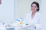 Portrait of a smiling woman taking tray with blood samples