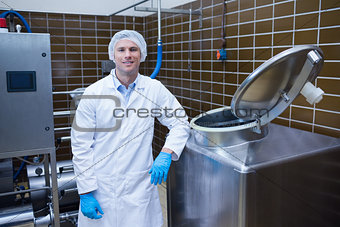 Smiling biologist leaning against storage tank