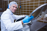 Smiling man in lab coat opening the lid of the machine