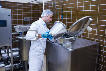 Smiling man in lab coat pouring something on the machine