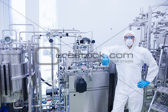 Scientist in protective suit leaning against machine