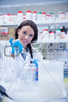 Smiling female scientist using a pipette