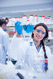 Portrait of a smiling chemist holding a beaker of blue liquid