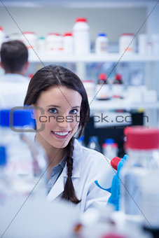 Smiling chemist picking up the bottles on the shelf