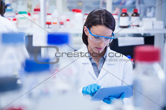 Chemist wearing safety glasses and using tablet pc
