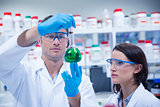 Chemist team looking beaker of green chemical