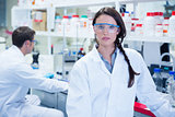 Unsmiling chemist standing in front of her colleague