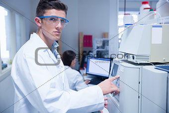 Unsmiling young chemist using the machine