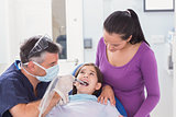 Pediatric dentist examining young patient with her mother