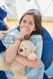 Scared patient covering mouth and holding teddy bear