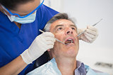Dentist examining a patient with tools