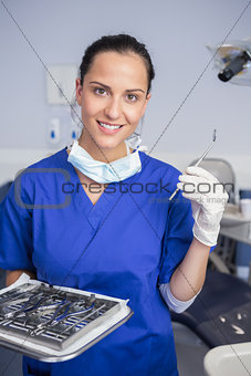 Smiling dentist holding tray and angle mirror