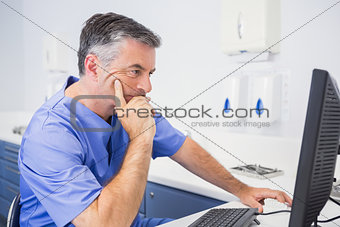 Serious dentist sitting and using computer