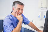 Portrait of a smiling dentist using computer