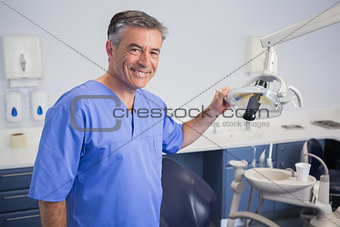 Portrait of a friendly dentist holding light