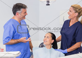 Smiling dentist and nurse speaking with their patient