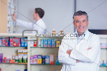 Smiling pharmacist standing with arms crossed