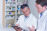 Man holding medication and his colleague writing a prescription