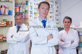 Smiling pharmacy team standing with arms folded