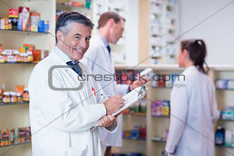 Smiling pharmacist in lab coat writing a prescription
