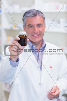 Pharmacist showing a drug bottle to camera