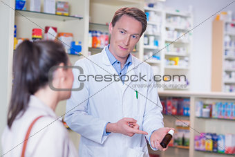 Pharmacist pointing a flask of pills in front of a customer
