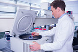Chemist in lab coat using a centrifuge