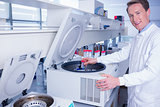 Smiling chemist using a centrifuge looking at camera