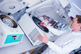 Chemist in lab coat using a centrifuge
