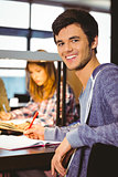 Portrait of a smiling student sitting at desk looking at camera