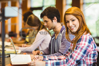 Student looking at camera while studying with classmates
