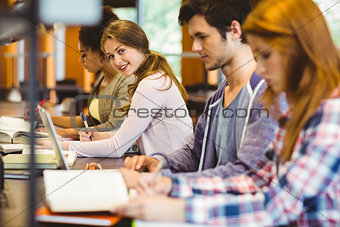 Student looking at camera while studying with classmates